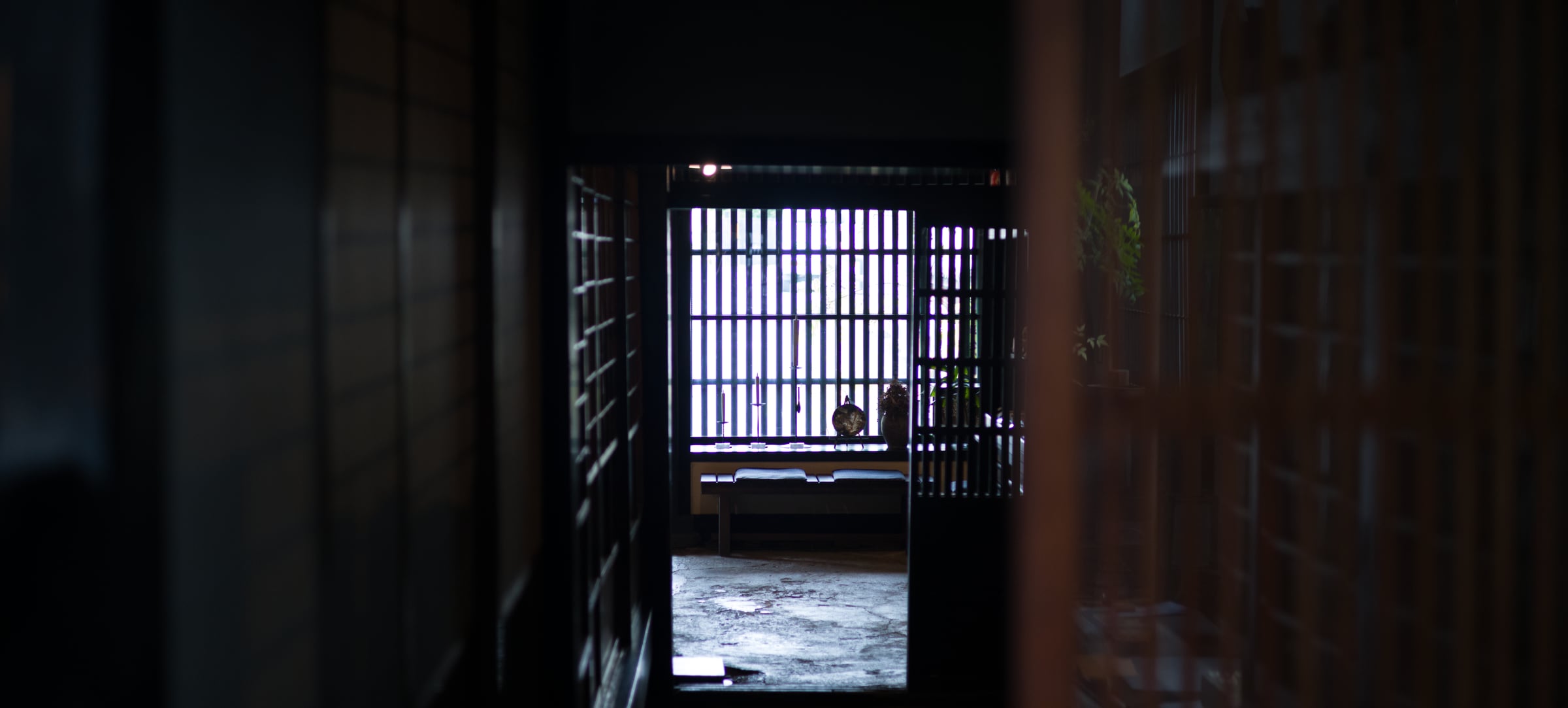 A lattice window lit at the end of a dark corridor in an old house (photo: Takahiro Mitsui)