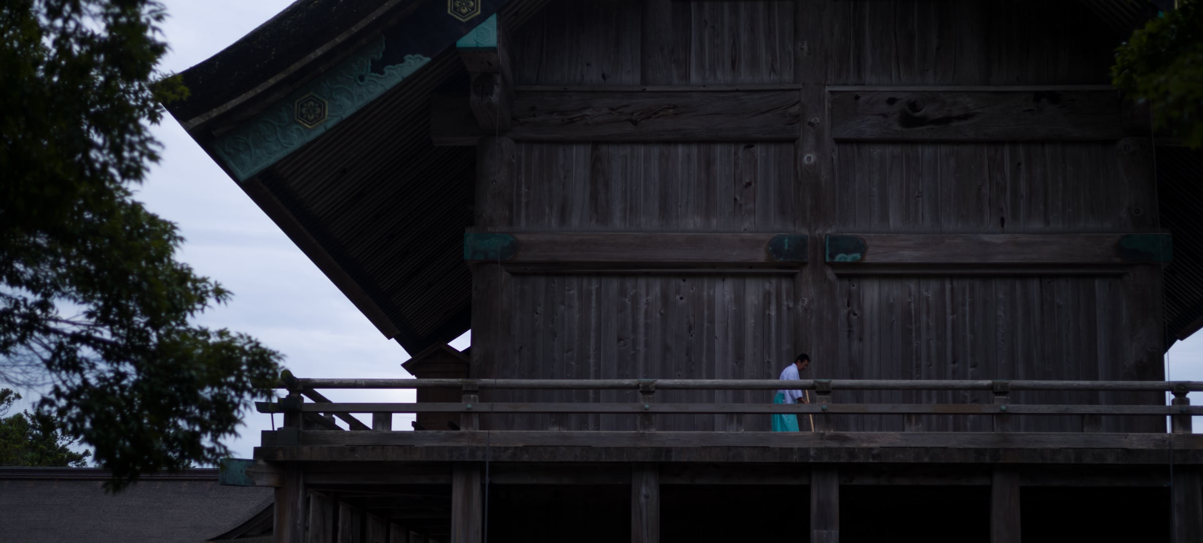 A figure in pale blue on the veranda of a towering wooden shrine hall (photo: Takahiro Mitsui)